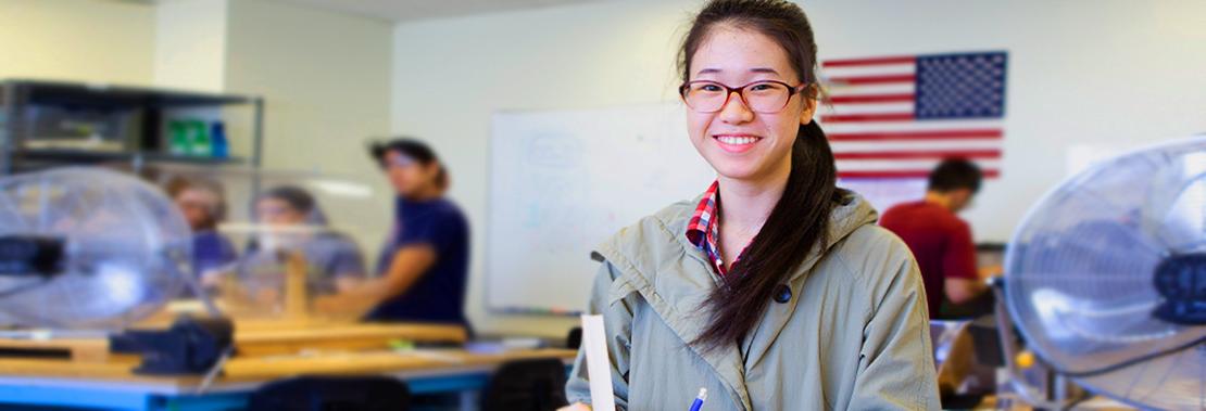 一名女学生站在工程学教室里微笑着